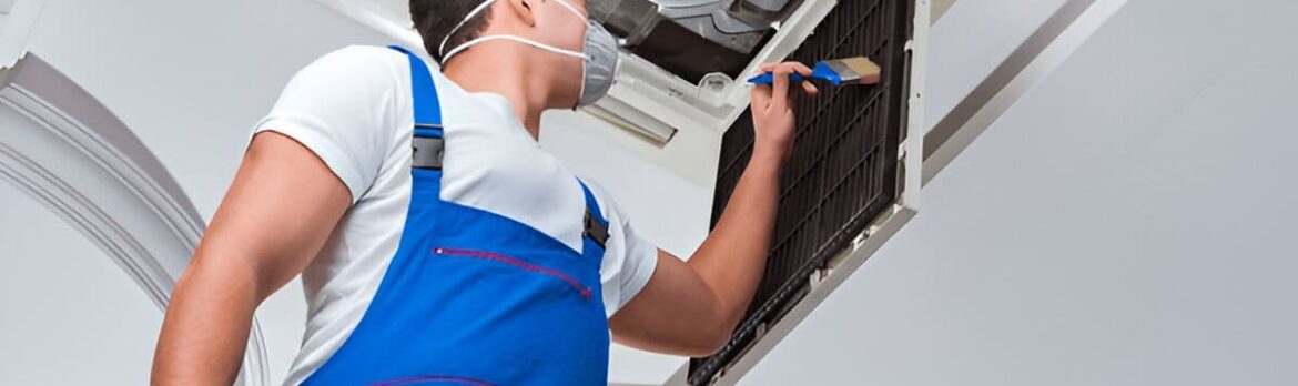 Technician cleaning rooftop AC with brush in Jumeirah Village Circle (jvc)