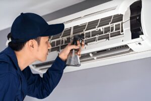Technician cleaning AC coil with water spray in al barsha